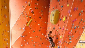 Una pared de escalar con diferentes agarraderas y una persona escalando.