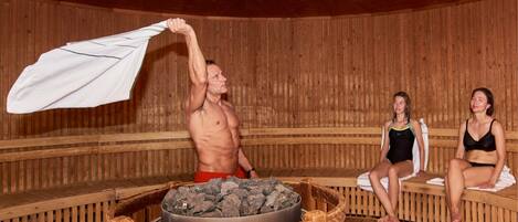 A sauna with wooden benches and a central stone heating area.