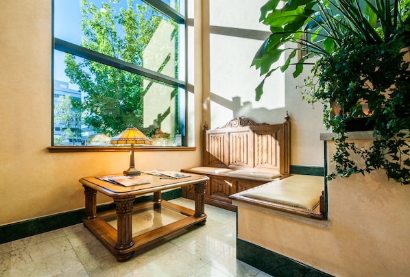 Une pièce dotée d’une grande fenêtre, d’une table en bois, d’un banc rembourré et d’une plante en pot.