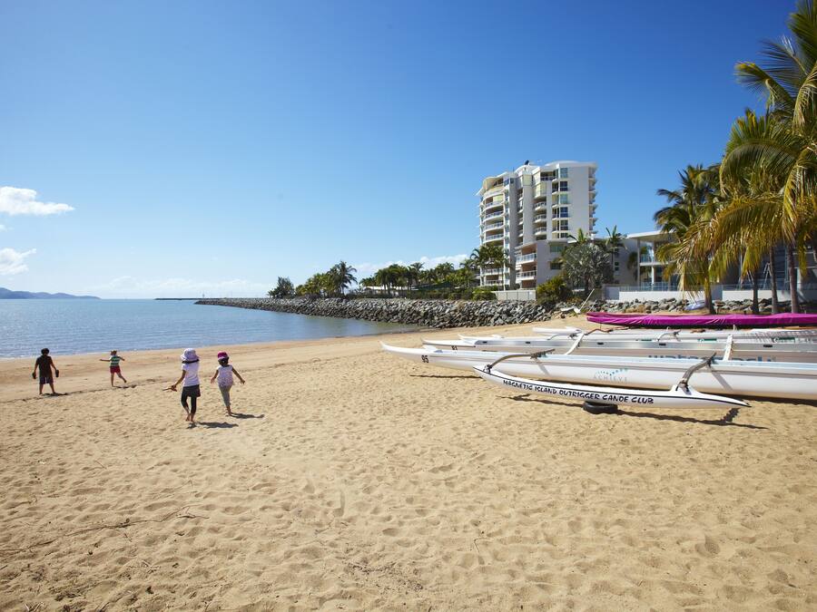 Ein Strand mit Kanus, einem Hotel und Palmen.