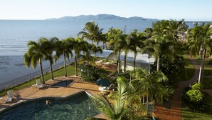 Un resort con piscina, palme e vista sul mare.