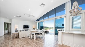 Un soggiorno moderno con zona pranzo, ampie finestre e vista sul mare.