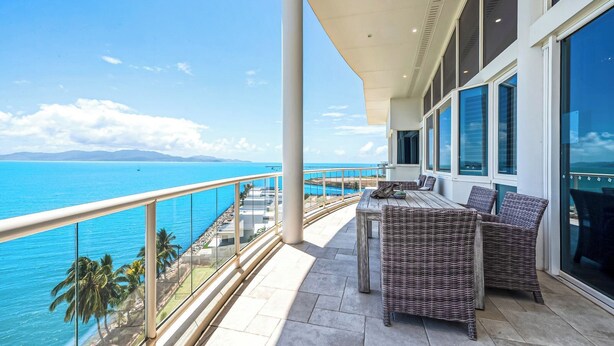 Un balcone con mobili in vimini, ampie finestre e vista sull'oceano.