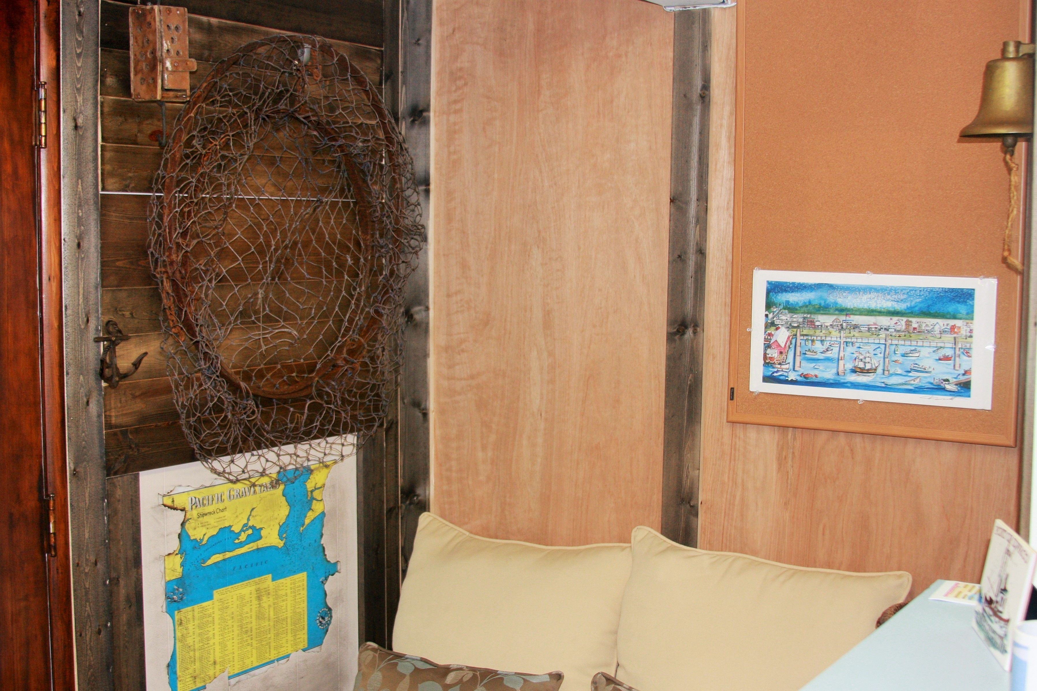 A room with a wooden door, a map on the wall, a bell, and a framed picture.