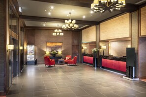 A spacious lobby with a reception desk, red seating area, and modern lighting fixtures. - Hilton Queenstown Resort & Spa (Kawarau Falls)