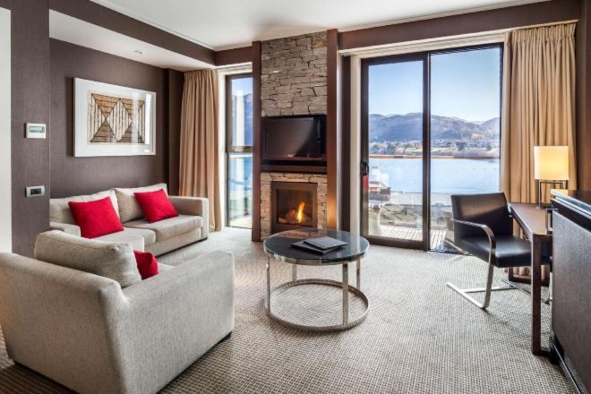 Une chambre d’hôtel avec une cheminée, un canapé, une table basse ronde et un téléviseur.