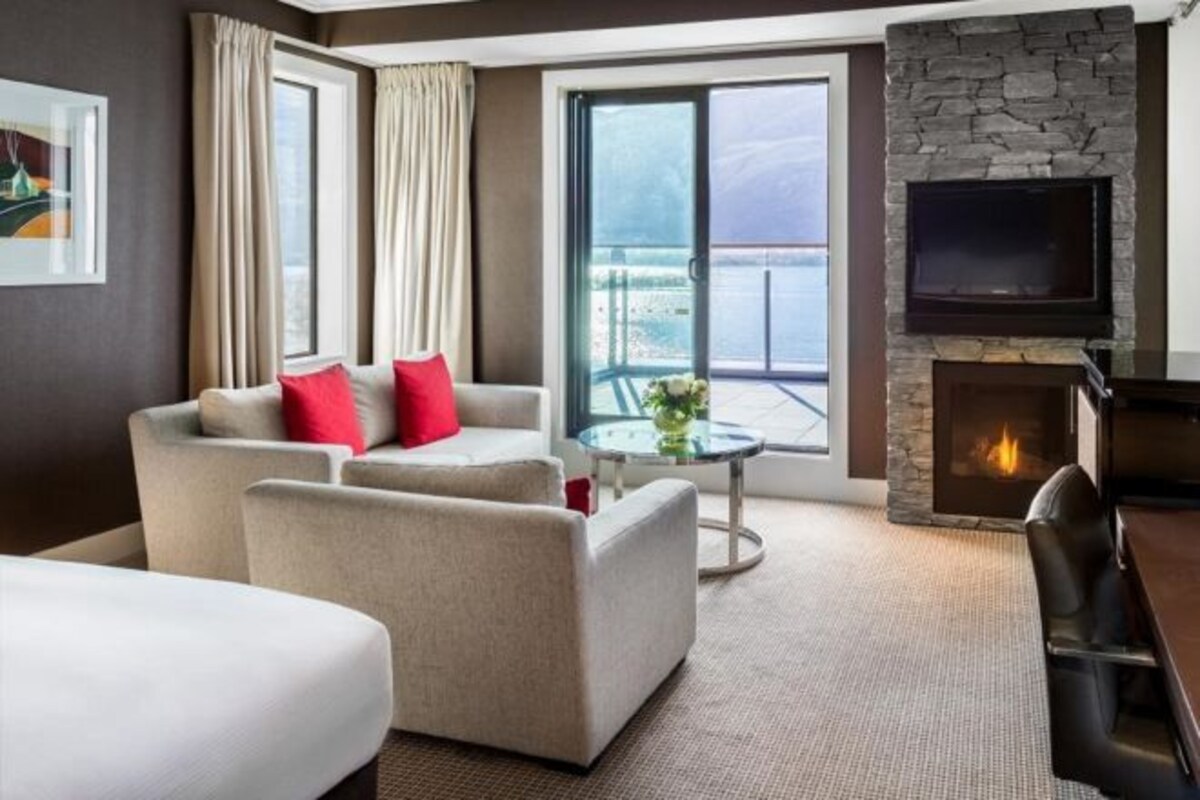 Un salon moderne comprenant un ensemble de canapés, une cheminée, un téléviseur à écran plat et un balcon avec vue.