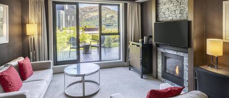 A modern living room with a fireplace, a sofa set, a round coffee table, and a large sliding glass door leading to an outdoor area.