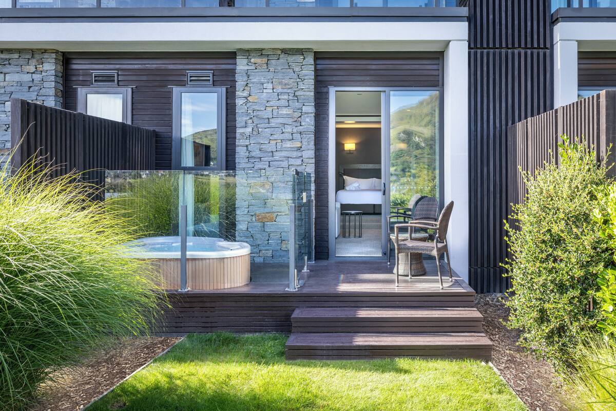 A modern building with a stone facade, a glass-enclosed outdoor seating area, and a hot tub.