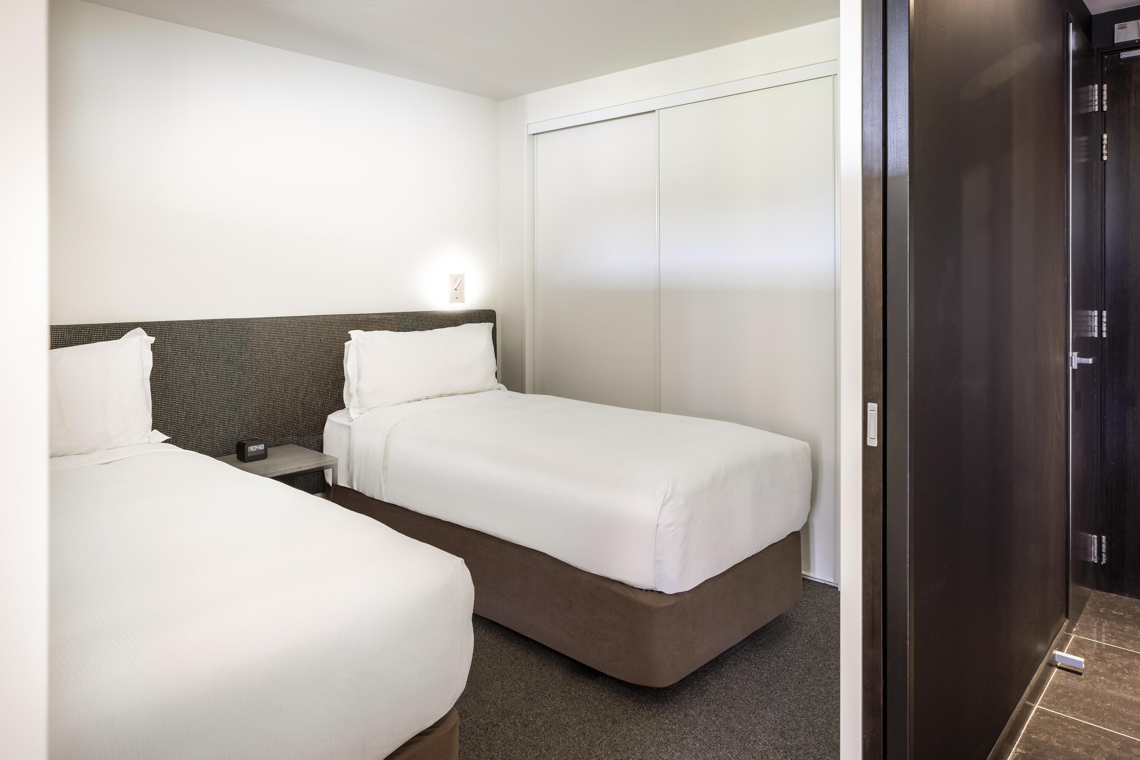 Ein Hotelzimmer mit zwei Betten, einem Kleiderschrank und einer Tür.