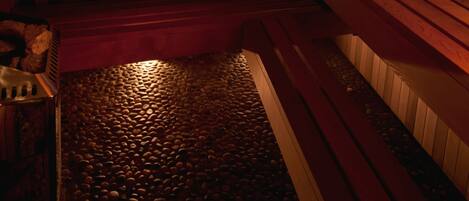 A sauna with wooden benches and a stone floor.