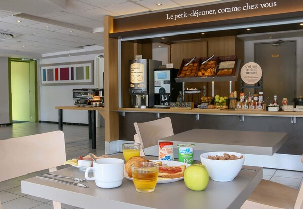 Desayuno con máquina de café, variedad de bollería, frutas y cereales.