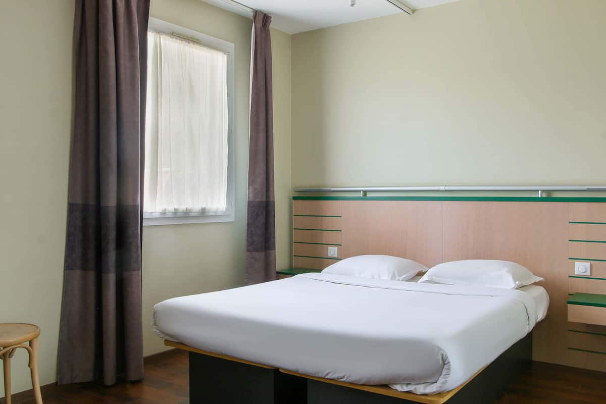 A neatly made bed with white linens, a wooden headboard, and a bedside table.