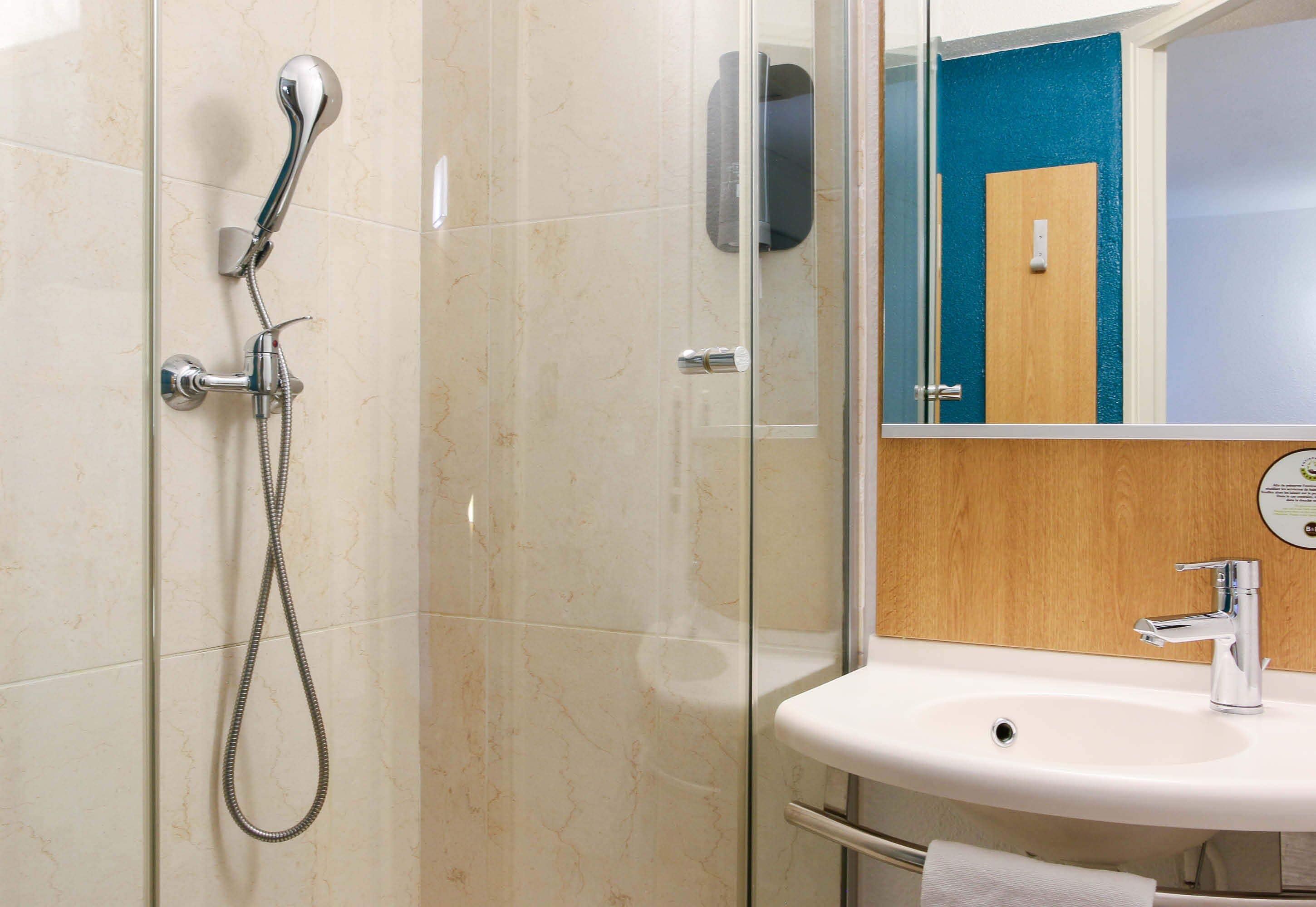 A modern bathroom with a glass-enclosed shower, a white sink, and a wooden vanity.