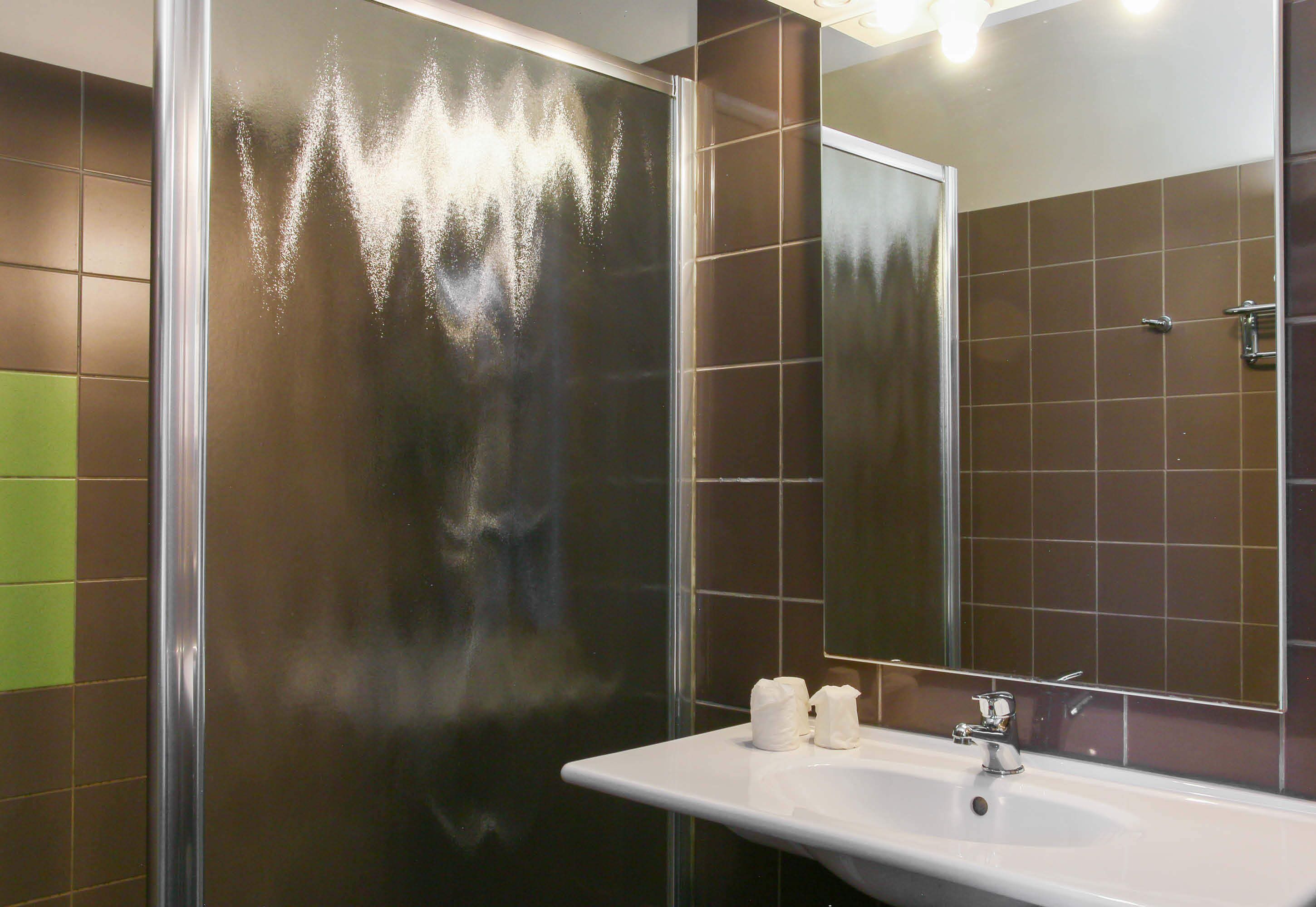 A bathroom with a glass shower enclosure, a white sink, and a mirror.