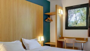 Una habitación de hotel con cama, lámparas de noche, un escritorio y una silla.