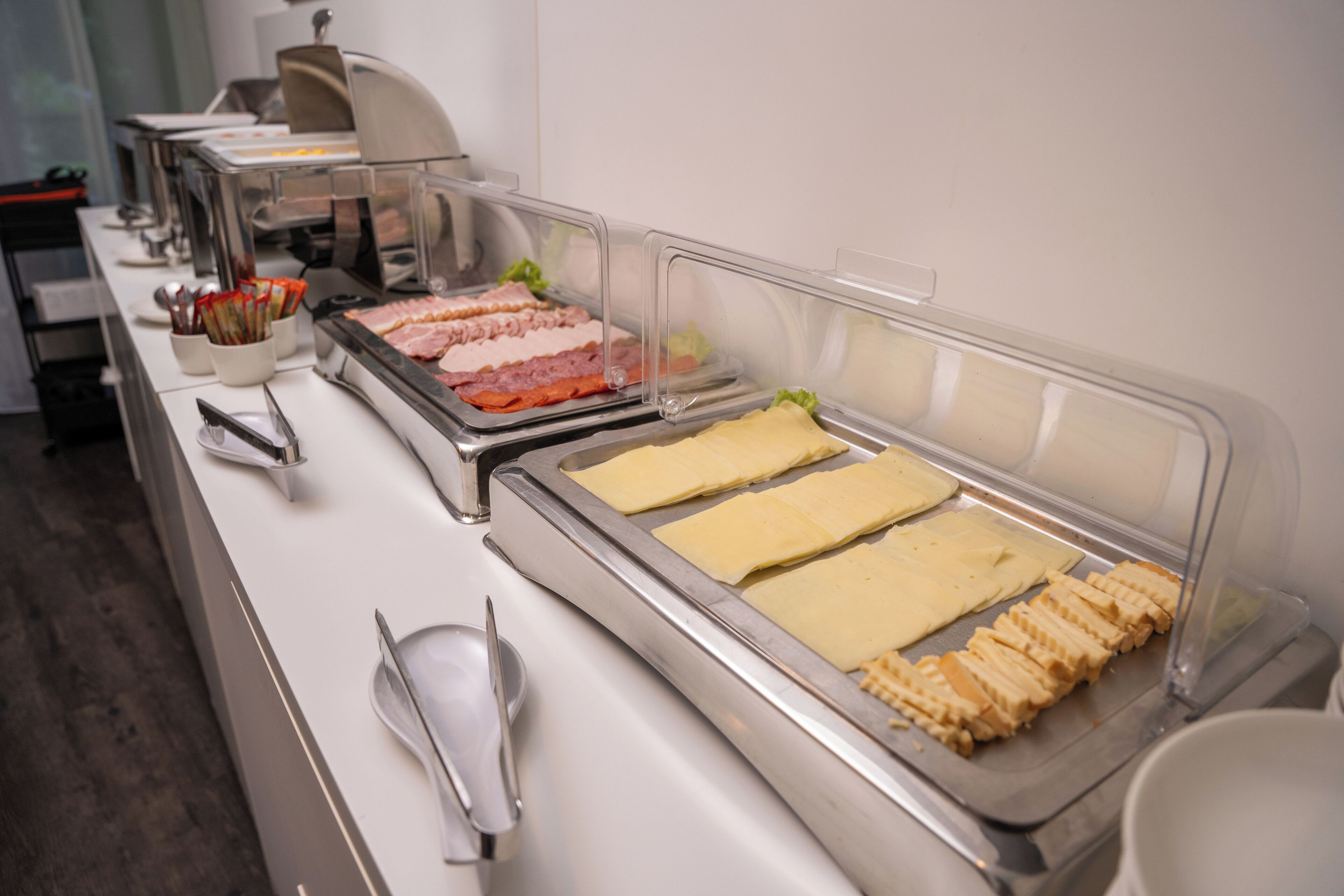 Un bufé con diferentes opciones de comida, incluyendo carnes y quesos, dispuestas en bandejas.