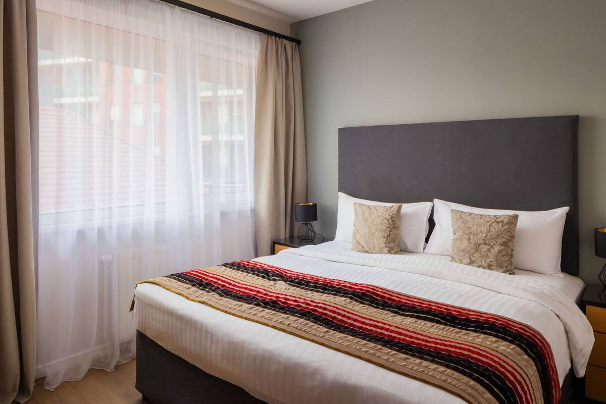 A neatly made bed with a striped blanket, a dark headboard, and two pillows.