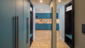 A modern kitchen with teal cabinets and a wooden floor. - Escala Hotel & Suites (Budapest)