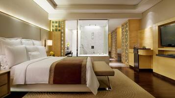 Habitación de hotel con una cama grande, televisión, baño con ducha y escritorio con lámpara.