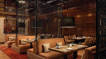A restaurant with wooden panel walls, cushioned seating, and tables set with plates and glasses.