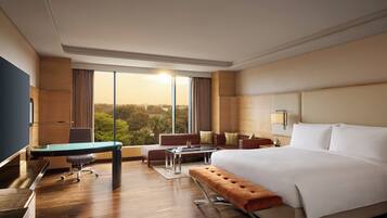 Habitación de hotel con una cama grande, un escritorio, un sofá y vistas al exterior.
