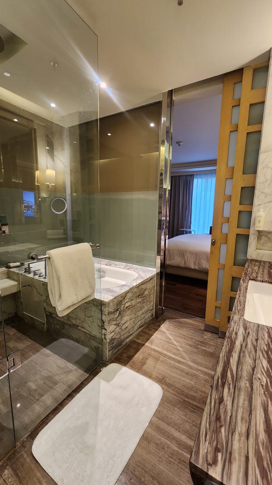 A modern bathroom with a marble sink, a bathtub, and a glass shower enclosure.
