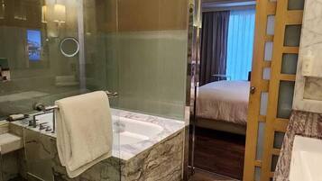 A modern bathroom with a marble sink, a bathtub, and a glass shower enclosure.