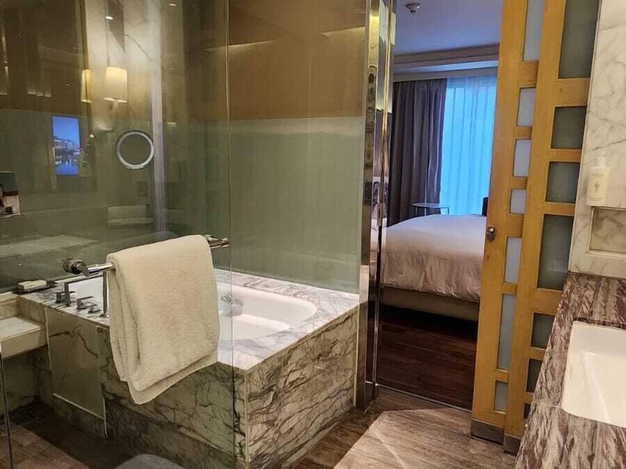 A modern bathroom with a marble sink, a bathtub, and a glass shower enclosure.