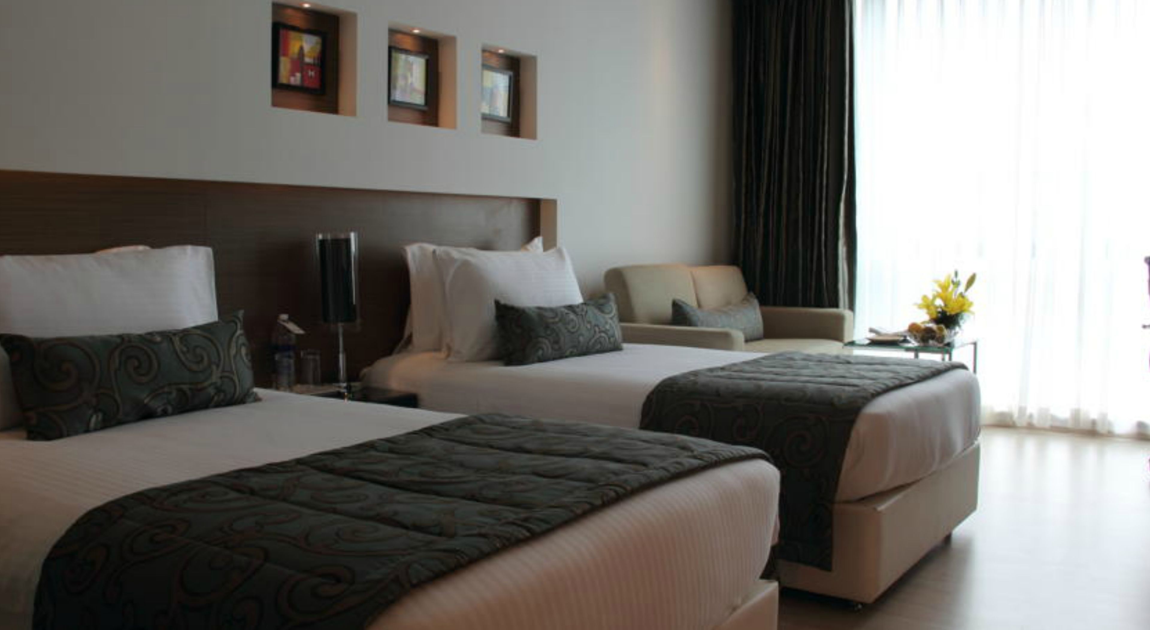 A hotel room with two beds, a sofa, and a desk.