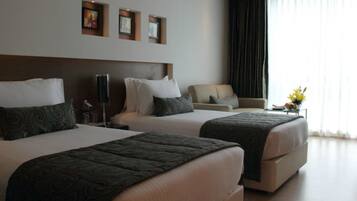 A hotel room with two beds, a sofa, and a desk.