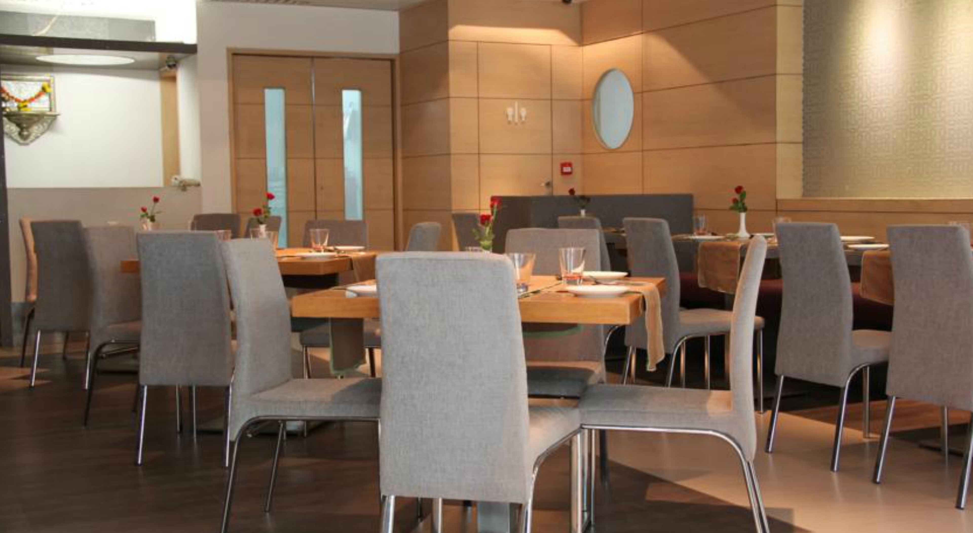 A conference room with a long table, grey chairs, and a wooden floor.
