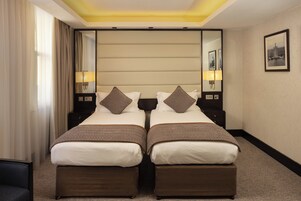 Ein Hotelzimmer mit zwei Betten, einem großen Spiegel und einem gerahmten Bild an der Wand.