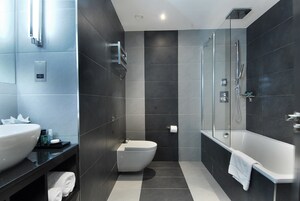 A modern bathroom with a large sink, toilet, and bathtub.