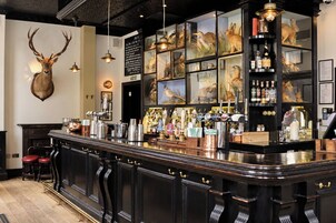 Eine Bar mit einer Theke, Hockstühlen und einer Auswahl an Flaschen und Gläsern.