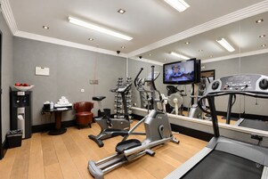 Una palestra con attrezzature per esercizi, un tapis roulant e uno schermo televisivo.