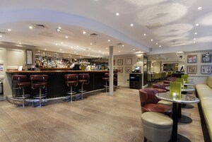 Eine Bar mit Hockern und einer Theke, umgeben von Tischen und Stühlen.
