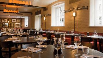 A restaurant with multiple dining tables, each set with plates, cutlery, and wine glasses.