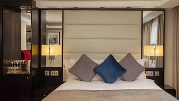Une chambre d’hôtel avec un grand lit, deux oreillers, une table de chevet, un miroir et une lampe fixée au mur.