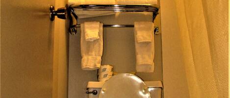 A toilet with a white seat and lid, a towel rack with two white towels, and a framed picture above the toilet.