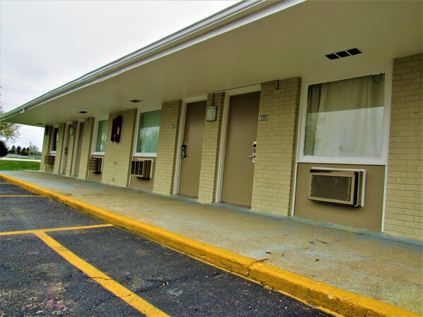 A motel with a row of single rooms, each with a door and window, and a parking lot in front.