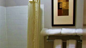 A bathroom with a bathtub, toilet, and a framed picture on the wall.