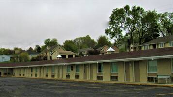Un motel con estacionamiento, una mesa de picnic y una hilera de habitaciones con fachada de ladrillo.