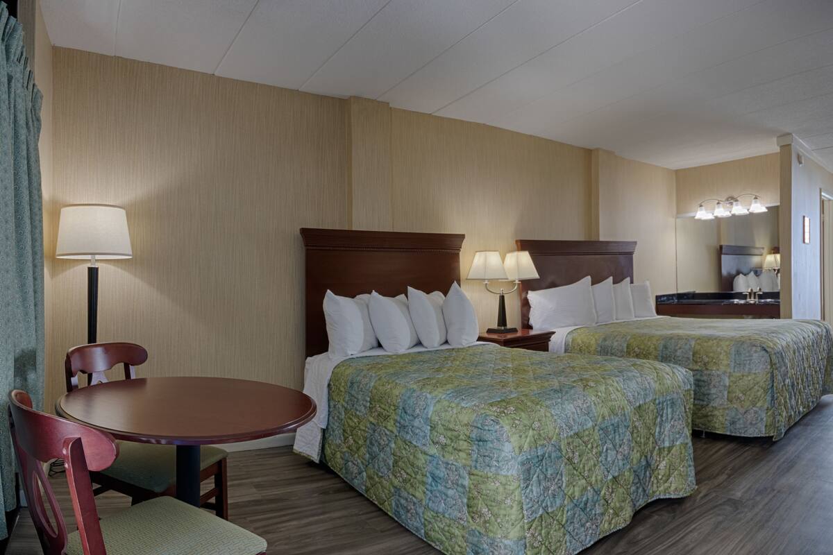 A hotel room with two beds, a desk, and a chair.
