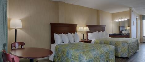 A hotel room with two beds, a desk, and a chair.