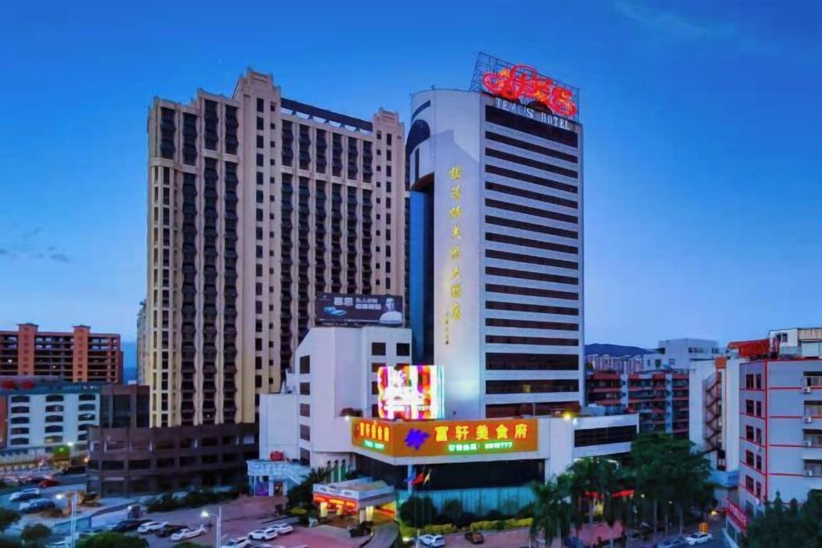 A hotel with multiple floors, a prominent sign, and a parking area in front.