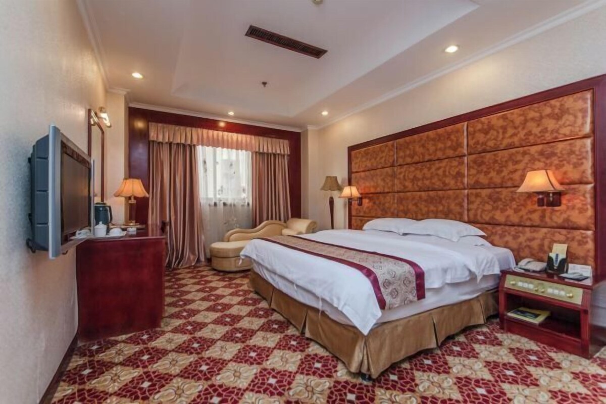 Habitación de hotel con una cama grande, televisor, escritorio y silla.