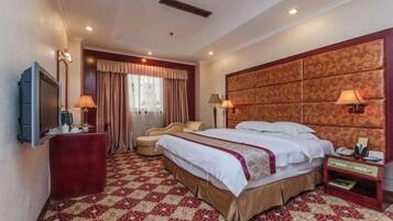 A hotel room with a large bed, a TV, a desk, and a chair.