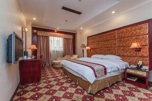 A hotel room with a large bed, a TV, a desk, and a chair. - Temeisi Hotel (Jieyang)