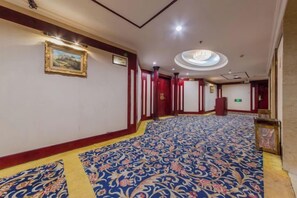 A hotel corridor with patterned carpet, framed artwork on the walls, and a reception desk. - Temeisi Hotel (Jieyang)